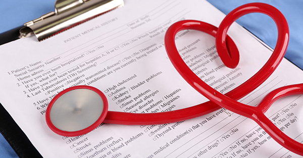 clipboard with patient's medical history form with a red stethoscope in the shape of a heart